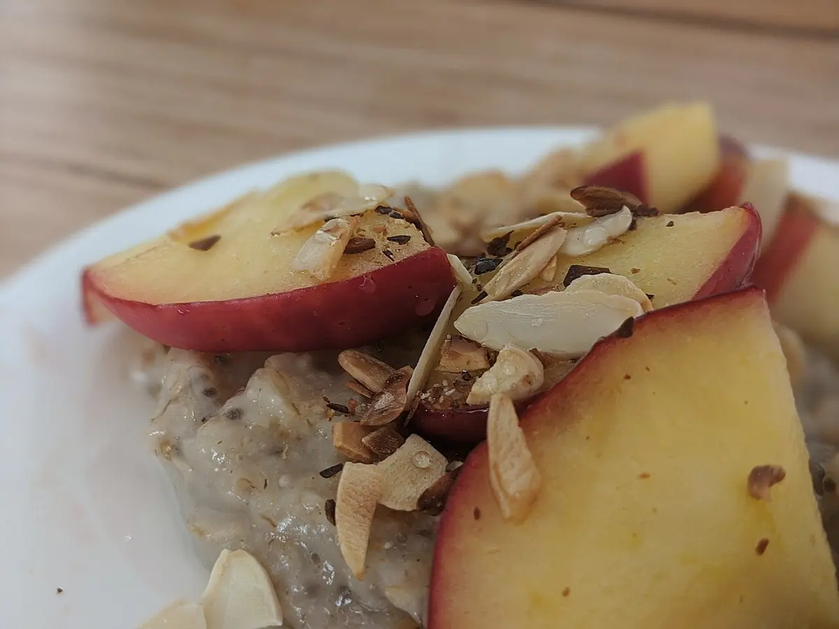 Prato de mingau de aveia coberto com fatias de maçã e lâminas de amêndoa