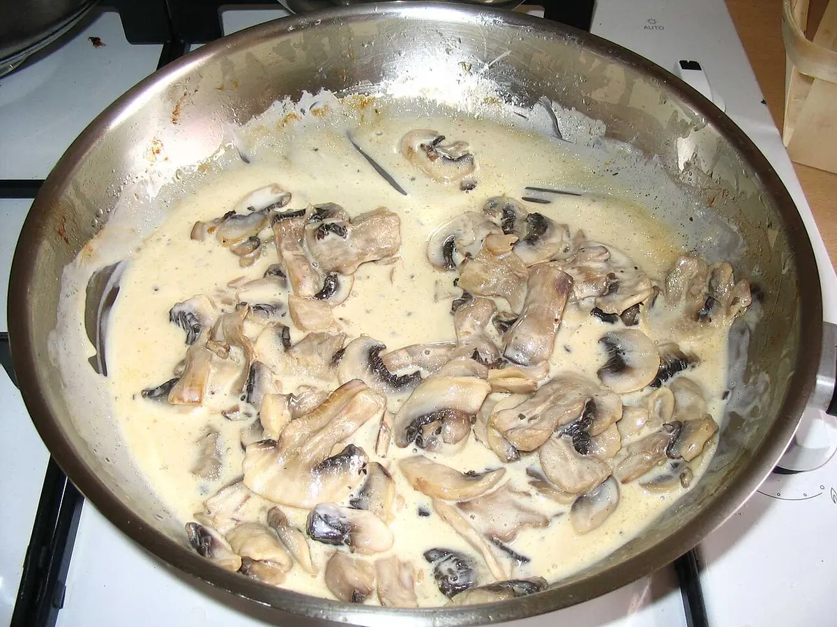Frigideira com cogumelos fatiados cozinhando num molho cremoso