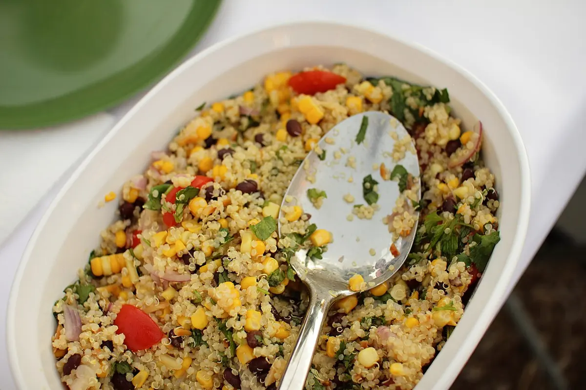 Travessa de salada de quinoa com milho, feijão, tomate e ervas frescas