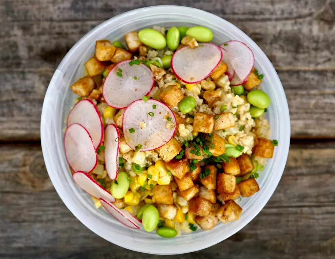 Tigela de cereais com cubos de tofu dourado, rabanete, milho e edamame