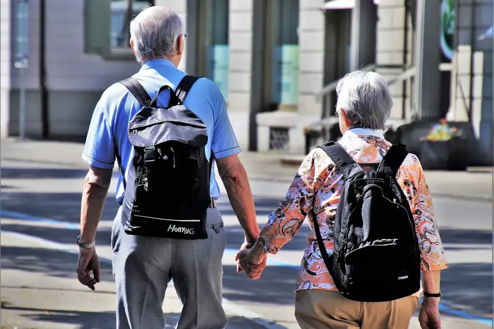 Casal de idosos, visto de costas, caminhando de mãos dadas pela rua