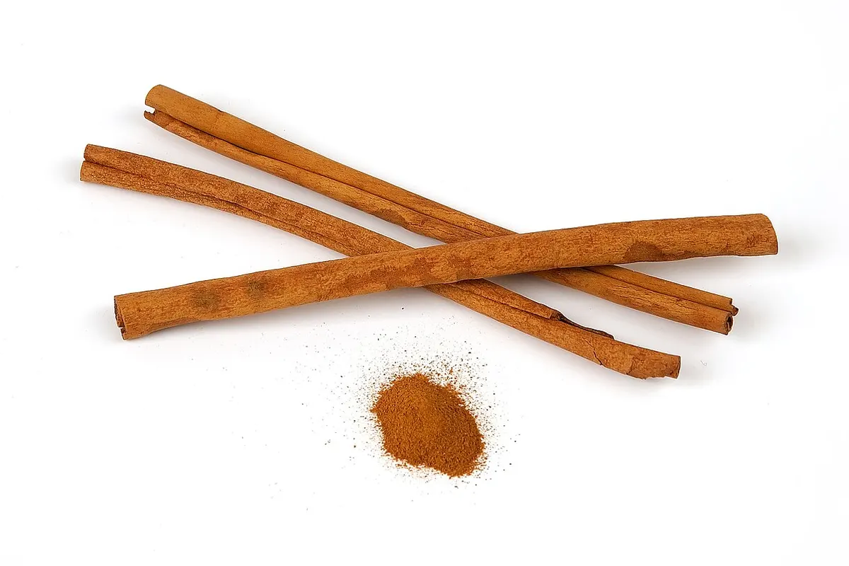 Paus de canela-do-ceilão ao lado de uma xícara de chá avermelhado