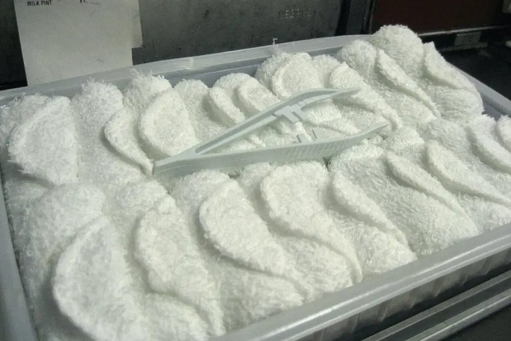 Bandeja com várias toalhas brancas dobradas e úmidas, preparadas para aplicação quente