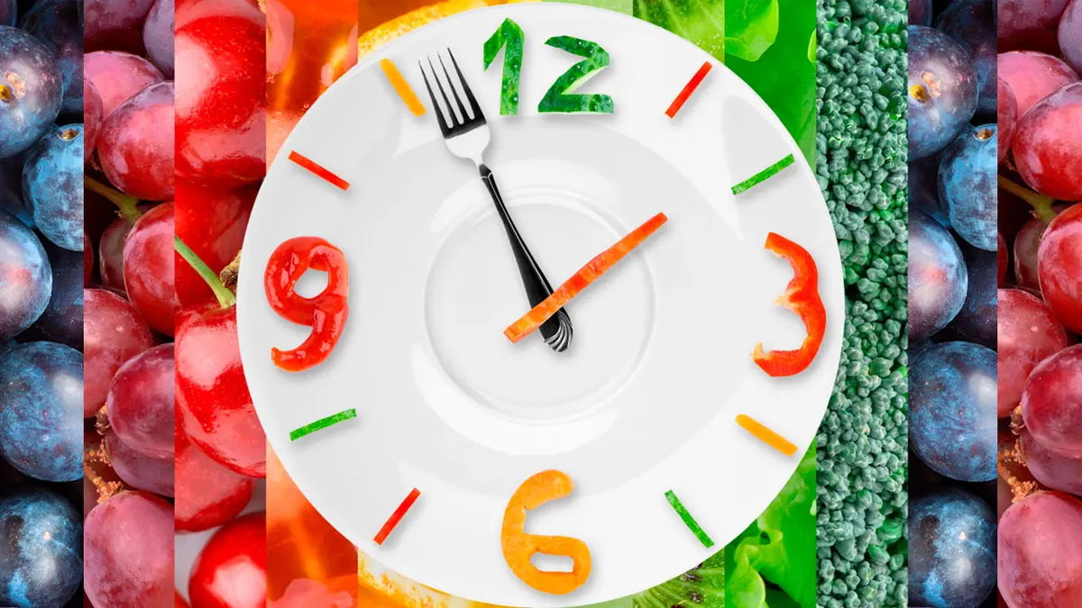 Relógio em forma de prato, com garfo e faca como ponteiros, sobre fundo de frutas e verduras